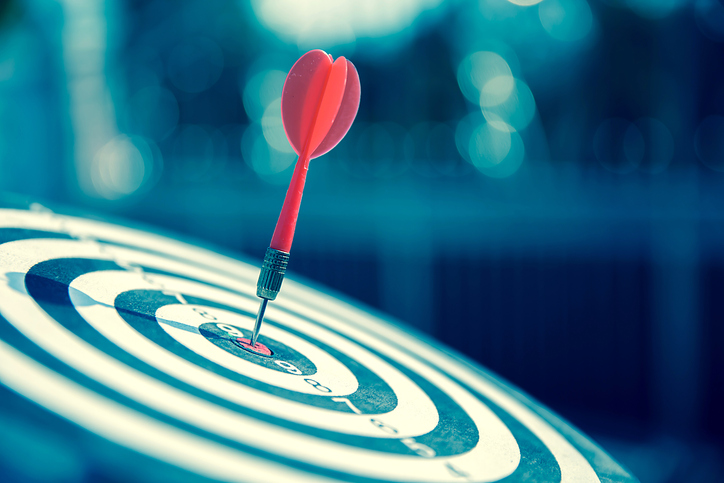 picture of a dartboard with a red dart in the bullseye